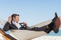 Smiling businessman lying in hamock taking off his tie Royalty Free Stock Photo