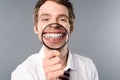 Smiling businessman with magnifier on grey background. Royalty Free Stock Photo