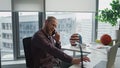 Smiling businessman phone conversation at office closeup. Man watching laptop Royalty Free Stock Photo