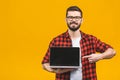 Smiling businessman pointing finger on blank laptop screen isolated over yellow background. Looking at camera Royalty Free Stock Photo