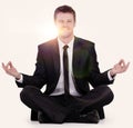 Smiling businessman relaxes sitting in the Lotus position