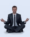 Smiling businessman relaxes sitting in the Lotus position