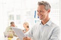 Smiling businessman scrolling on a tablet