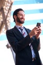 Smiling businessman sending text message on mobile phone