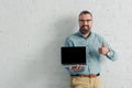 Smiling businessman showing thumb up and holding laptop with copy space Royalty Free Stock Photo