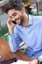 Smiling businessman sitting in cafe and talking on mobi