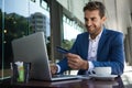 Smiling businessman sitting outside at a cafe table shopping online Royalty Free Stock Photo