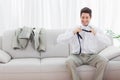 Smiling businessman sitting on sofa loosening his tie