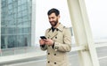 Smiling businessman with smartphone in airport. Young businessman typing text message on his way to work