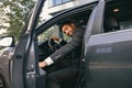 Smiling businessman in suit looking at camera while sitting in driver seat with opened door Royalty Free Stock Photo