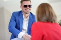 Smiling businessman in sunglasses shakes hands with woman in friendly handshake. Royalty Free Stock Photo