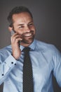 Smiling businessman talking on his cellphone against a gray back Royalty Free Stock Photo
