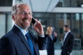 Smiling businessman talking on mobile phone in office corridor Royalty Free Stock Photo