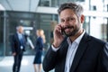 Smiling businessman talking on mobile phone in office corridor Royalty Free Stock Photo