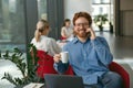 Smiling businessman talking phone with client while sitting in modern office and working on laptop Royalty Free Stock Photo