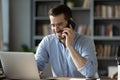 Smiling businessman talking on phone, looking at laptop screen Royalty Free Stock Photo