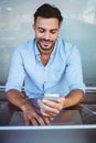 Smiling businessman using phone while working on laptop Royalty Free Stock Photo