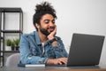 Smiling businessman wearing casual wear is sitting typing on lap