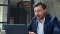 Smiling businessman working with laptop computer and papers in office. Royalty Free Stock Photo