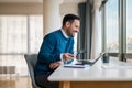 Smiling businessman working on laptop while sitting at office desk Royalty Free Stock Photo