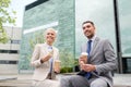 Smiling businessmen with paper cups outdoors