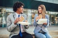 Smiling businessmen with sandwiches sitting in front of the office building Royalty Free Stock Photo