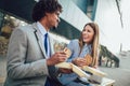 Smiling businessmen with sandwiches sitting in front of the office building Royalty Free Stock Photo