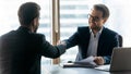 Smiling businessmen shake hands get acquainted in office