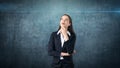 Smiling businesswoman with arms folded looking up at copyspace. Standing over gray background. Royalty Free Stock Photo