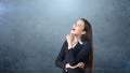 Smiling businesswoman with arms folded looking up at copyspace. Standing over gray background. Royalty Free Stock Photo