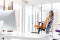 Smiling businesswoman carrying orange chair in new office