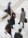 Smiling Businesswoman With Cellphone Amid Blurred Walking People