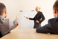 Smiling businesswoman drawing a graph for her colleagues on the whiteboard Royalty Free Stock Photo