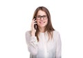 Smiling businesswoman in glasses talking on mobile phone. Beautiful young girl in white shirt on white isolated background talking Royalty Free Stock Photo