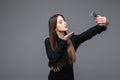 Smiling businesswoman making selfie photo on smartphone. Standing over gray background Royalty Free Stock Photo