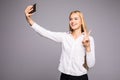 Smiling businesswoman making selfie photo on smartphone. Standing over gray background Royalty Free Stock Photo