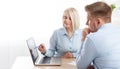 Smiling businesswoman and male manager going over paperwork together and working on a laptop at a table in an office. Concept Royalty Free Stock Photo