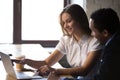 Smiling businesswoman mentor helping African American intern with work Royalty Free Stock Photo