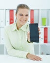 Smiling businesswoman in office hold cellphone in hands and show screen to camera.