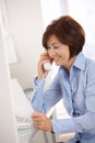 Smiling businesswoman on phone call reading paper. Royalty Free Stock Photo