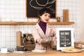 Smiling businesswoman placing menu board on bar counter in coffee shop.