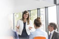 Smiling businesswoman planning strategy with colleagues during meeting at office