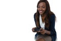 Smiling businesswoman playing video game while sitting on stool