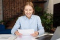 Smiling businesswoman reading documents when working at home