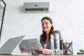 Businesswoman reading newspaper while sitting at workplace under air conditioner Royalty Free Stock Photo