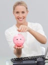 Smiling businesswoman saving money in a piggibank Royalty Free Stock Photo