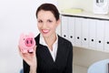 Smiling businesswoman saving money in a piggy-bank Royalty Free Stock Photo