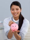 Smiling businesswoman saving money in a piggybank