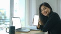 Businesswoman showing smart phone with blank screen while sitting in front of laptop computer in office. Royalty Free Stock Photo