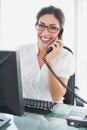 Smiling businesswoman sitting at her desk talking on the phone Royalty Free Stock Photo